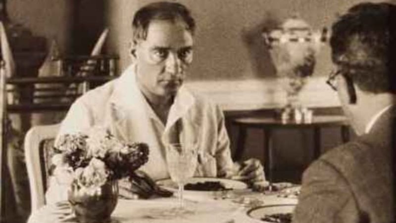 Atatürk seyahatte, beyaz gömlekle sofra başında; masada çiçekler ve su bardağı — 1930'lar arşiv fotoğrafı